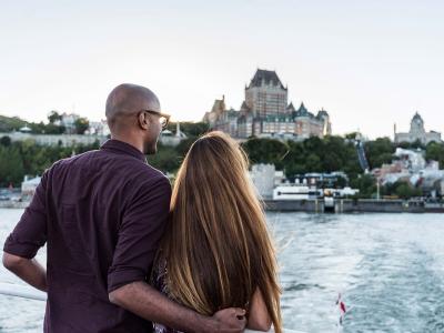 Couple aboard the Québec-Lévis ferry, admiring the panorama of Old Québec in summer.
