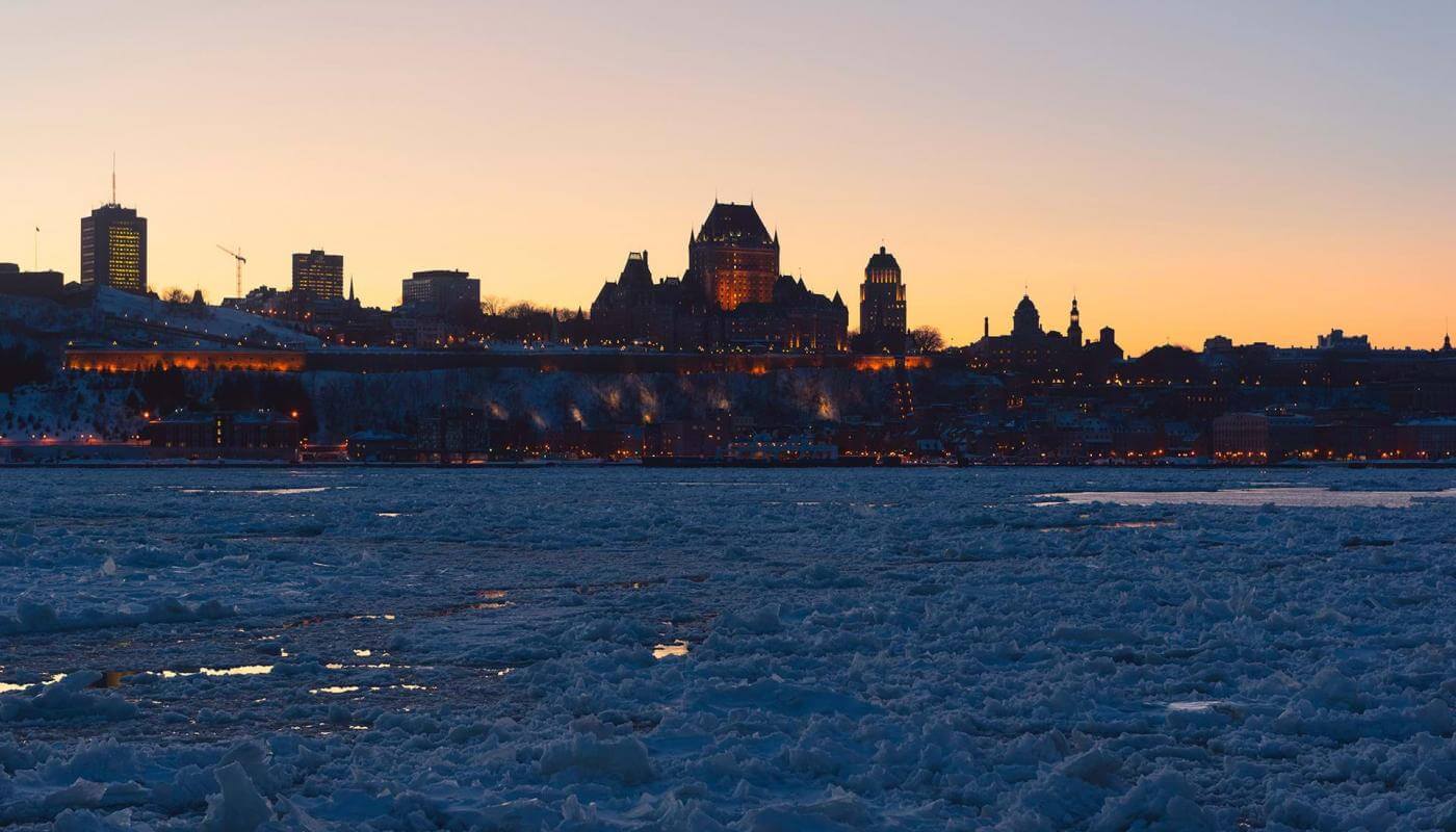 Panorama du Vieux-Québec en hiver, fleuve Saint-Laurent glacé et coucher de soleil, à partir de la Rive-Sud.