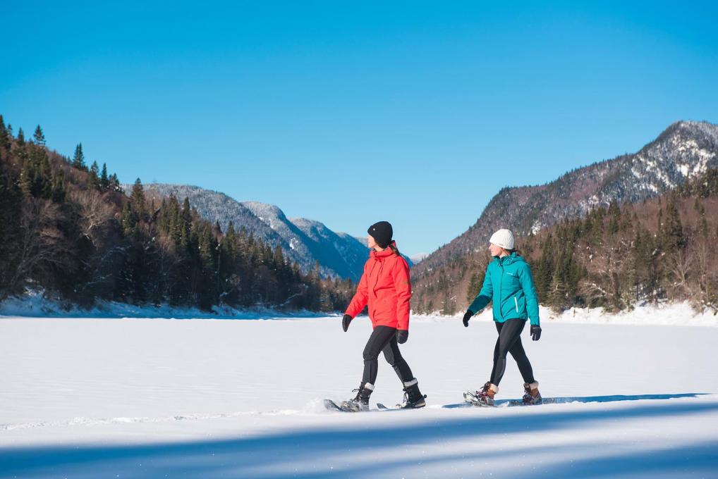 Deux filles en raquette profitent d'une journée ensoleillée d'hiver au parc national de la Jacques-Cartier.