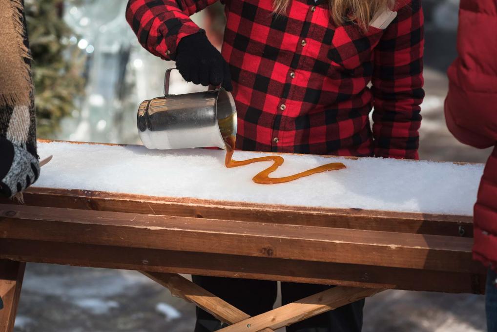 Du sirop d'érable chaud est versé sur de la neige pour en faire de la tire, une friandise sucrée. 