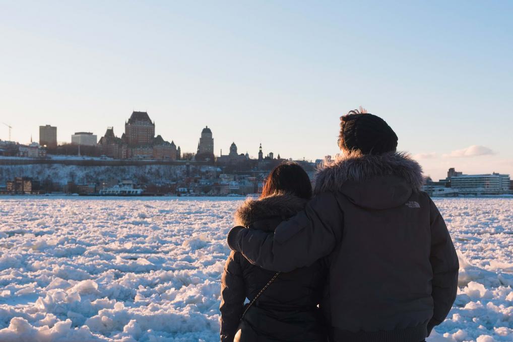Un couple regarde le fleuve Saint-Laurent glacé et le panorama du Vieux-Québec à partir de Lévis.