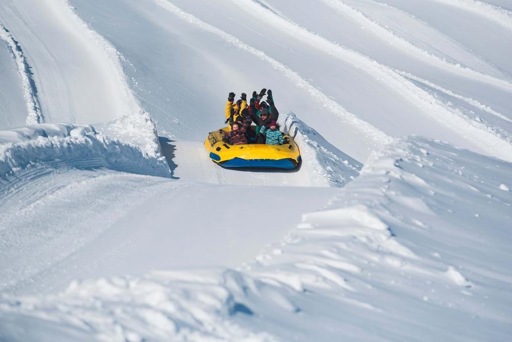 Des personnes font du rafting sur neige dans une glissade du Village Vacances Valcartier.