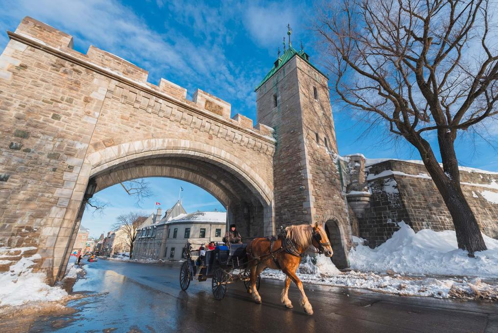  Two tourists in horse-drawn carriages pass under the Saint-Louis Gate in winter.