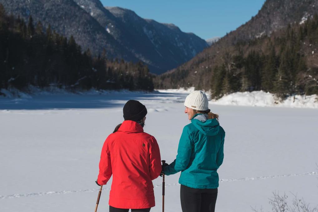 Two girls take a break in front of the snowy landscape of Jacques Cartier National Park.