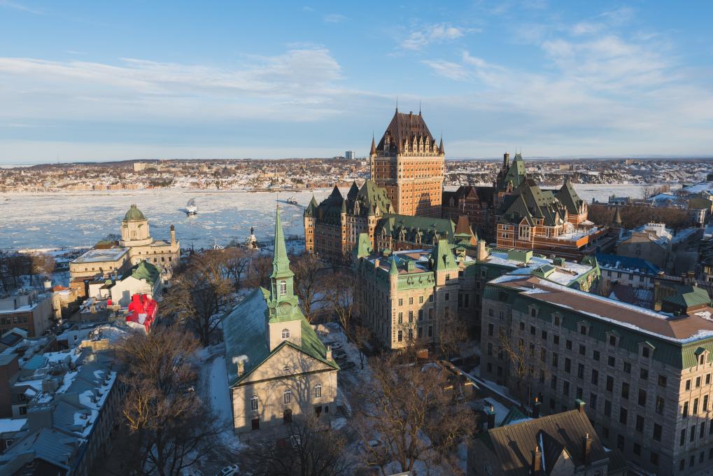Vue aérienne du Vieux-Québec en hiver, avec le fleuve Saint-Laurent glacé, le Château Frontenac et l'église Holy Trinity. 
