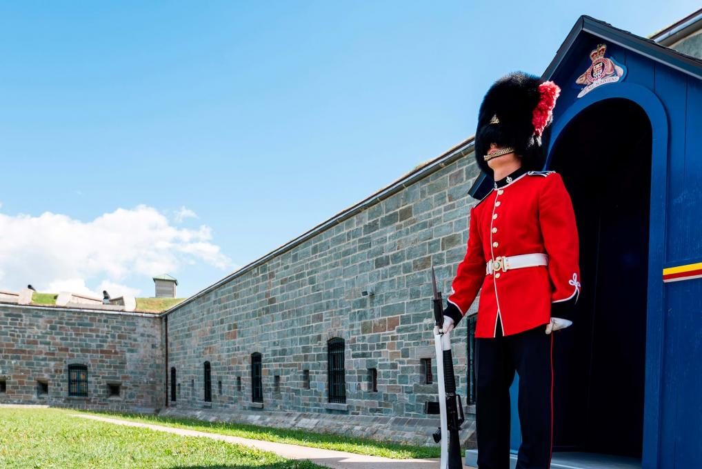 Un garde vêtu de l'uniforme traditionnel devant la porte d'entrée de la Citadelle de Québec.