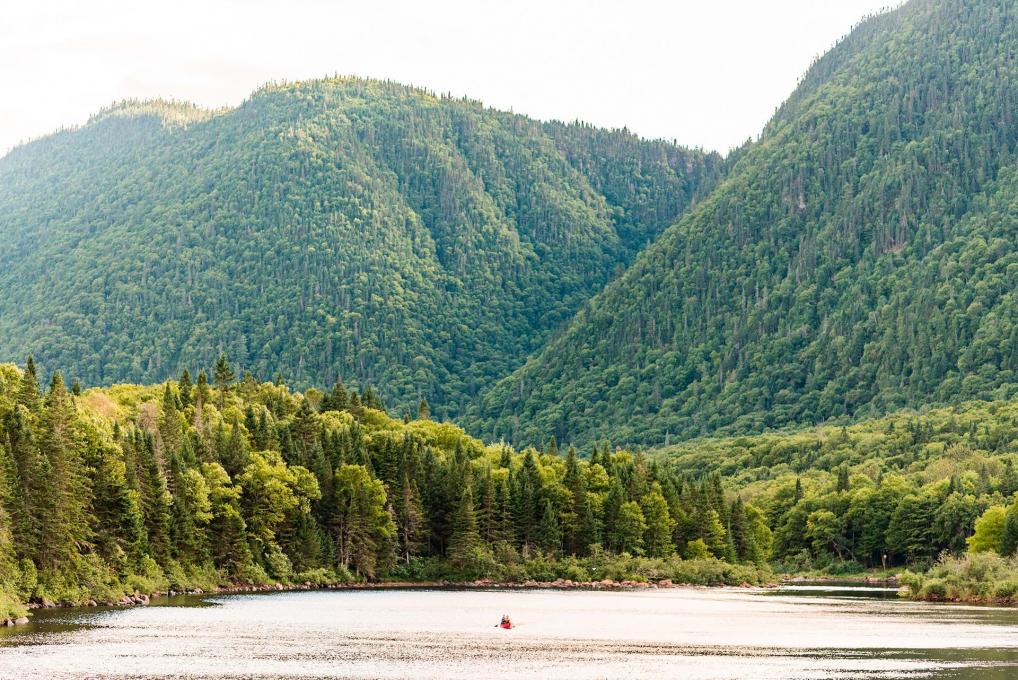 Landscape of the Jacques-Cartier Valley with a distant canoe in the river, in Jacques-Cartier National Park.
