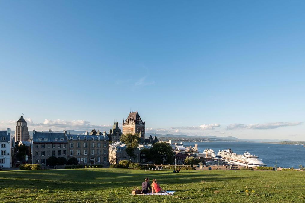 Couple picnic near the Pierre-Dugas-De Mons terrace, in front of a panorama of Old Québec and the St. Lawrence River.