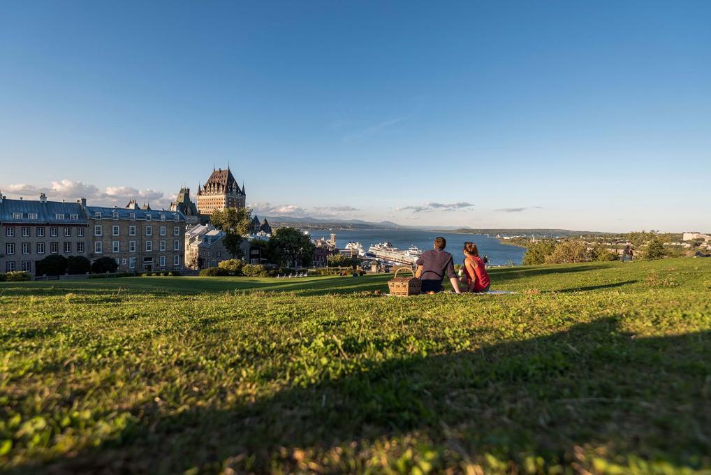 Couple picnicking near the Pierre-Dugua-De Mons terrace while admiring the Château Frontenac and the St. Lawrence River.
