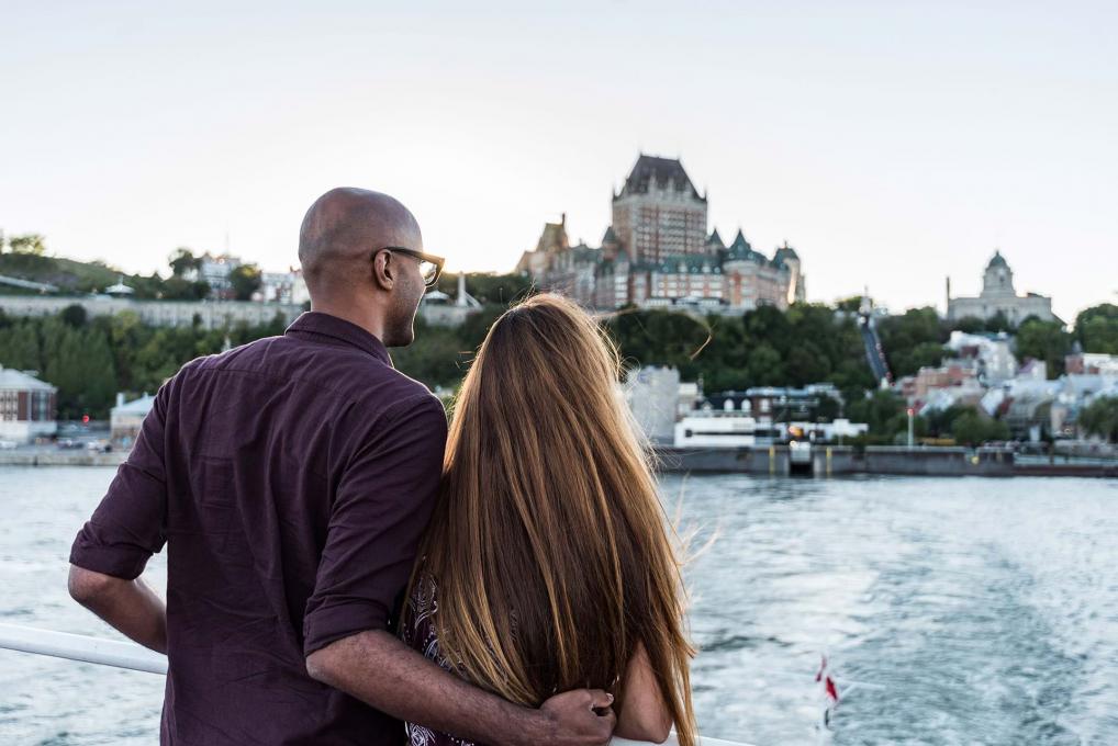 Couple aboard the Québec-Lévis ferry, admiring the panorama of Old Québec in summer.