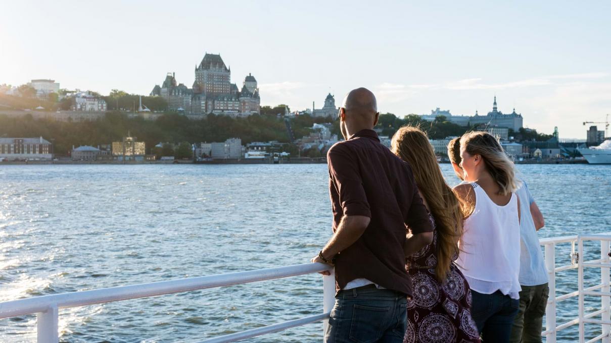 Group of friends aboard the Québec-Lévis ferry, admiring Old Québec in summer.