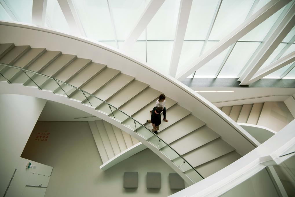 Un couple descend l'escalier intérieur du pavillon Pierre Lassonde au Musée national des beaux-arts du Québec.