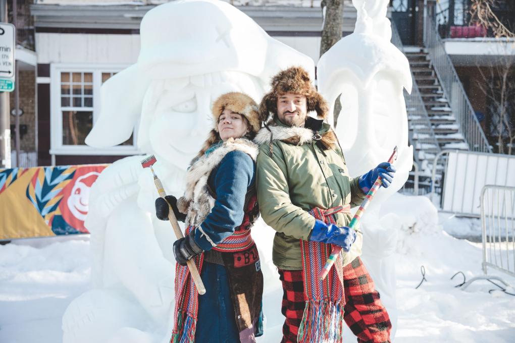 Deux personnages folkloriques devant une sculpture de neige au Carnaval de Québec