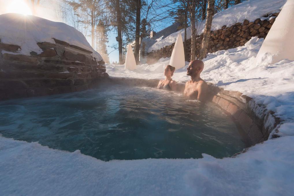 Un couple relaxe dans un spa nordique, en hiver.