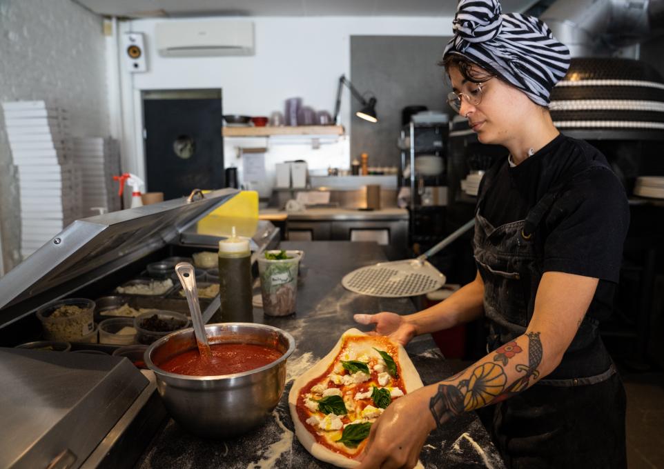 A cook prepares a pizza at Nina Pizza Napolitaine