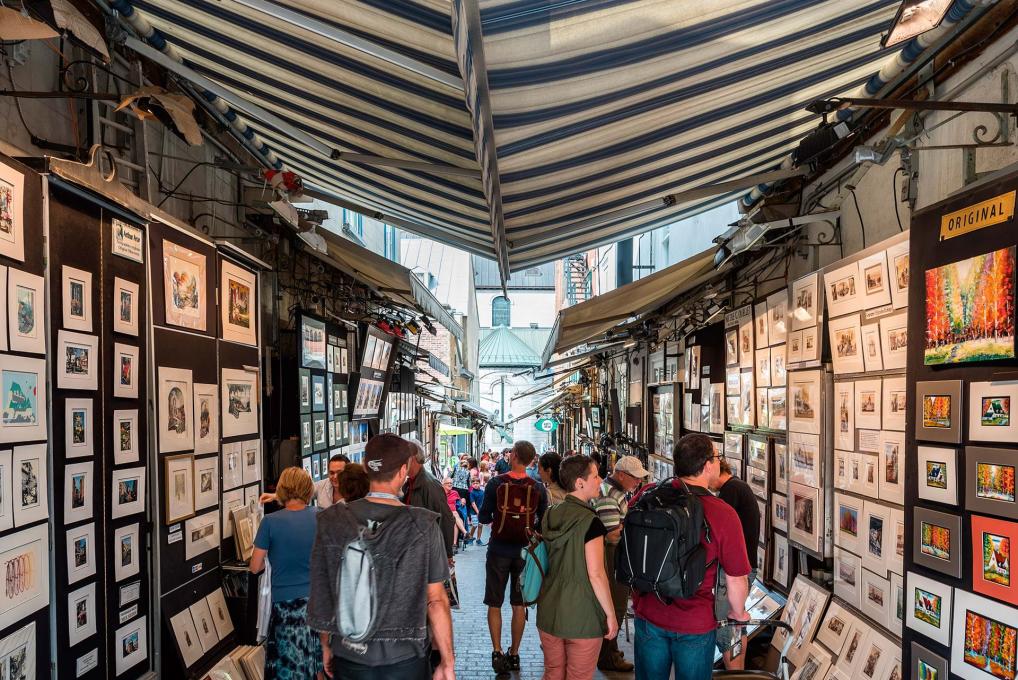 Visitors and artists chat on rue du Trésor, where several artists exhibit their works.