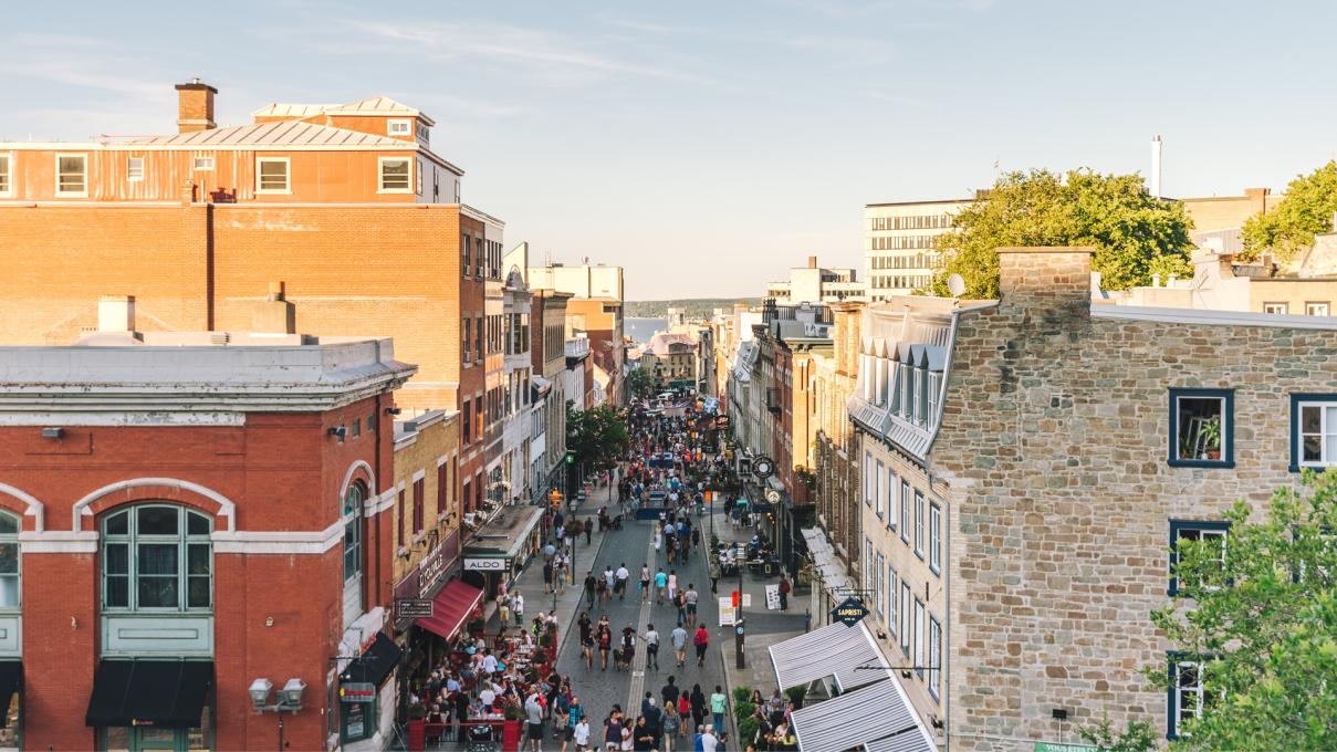 Plusieurs piétons se promènent sur la rue Saint-Jean en été.