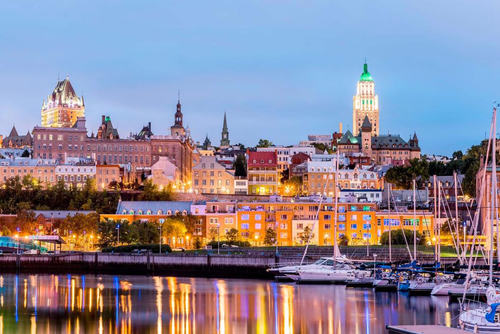 Voiliers au bassin Louise, dans le Vieux-Port de Québec, avec vue sur le Vieux-Québec illuminé.