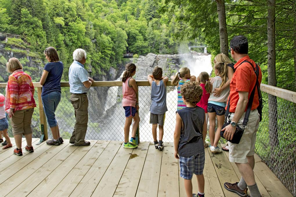 Several people, adults and children, observe the fall from the lookout at Canyon Sainte-Anne.