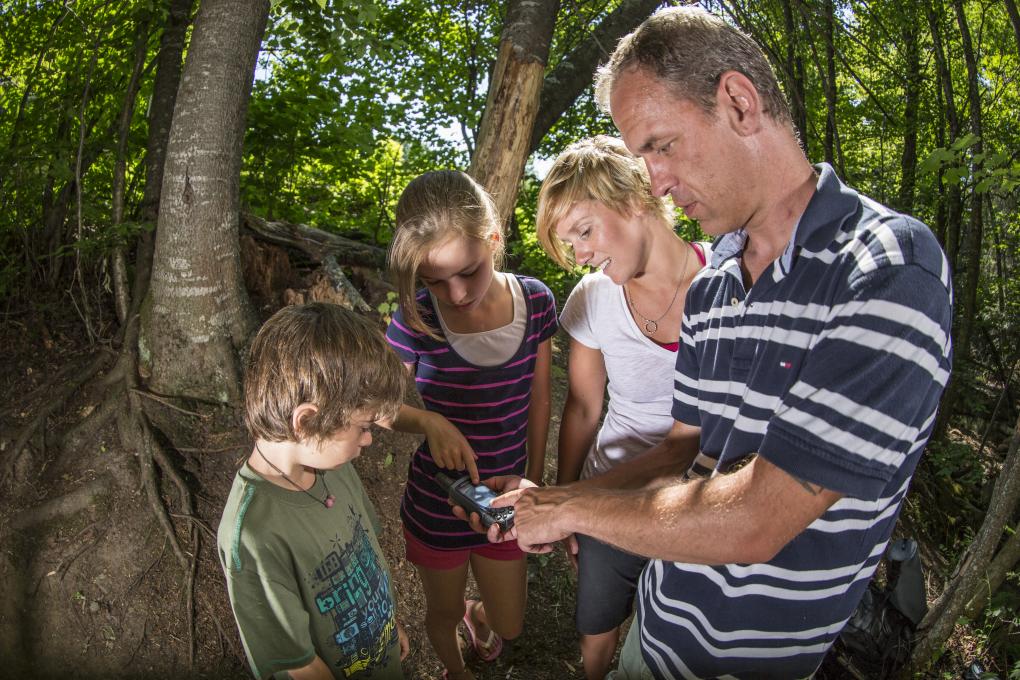 Une famille participe à l'activité de géocaching et randonnée à la Station touristique Stoneham, en été.