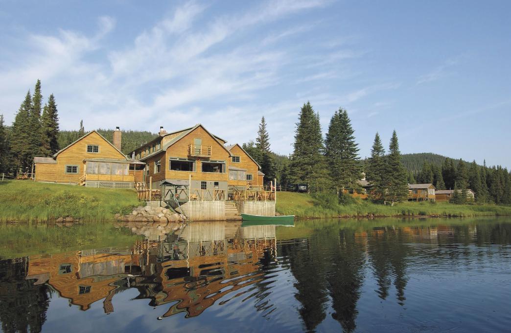 Exterior view of several chalets on the edge of a lake, in the Réserve faunique des Laurentides, in summer.