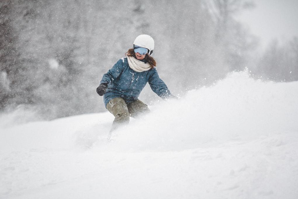A woman is snowboarding in powder snow at Stoneham Ski Resort.