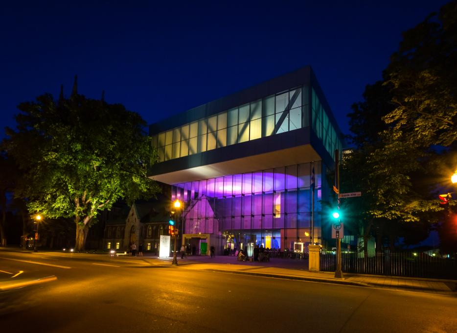Exterior view of the illuminated Pierre Lassonde Pavilion at the Musée national des beaux-arts du Québec in the evening, in summer.