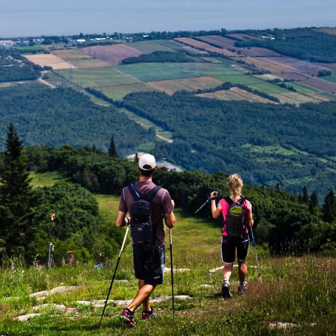 Un couple fait une randonnée pédestre au sommet du Mont-Sainte-Anne avec la vue sur le fleuve Saint-Laurent.