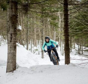 Une personne fait du fatbike dans les sentiers de vélo au Mont-Sainte-Anne, en hiver.