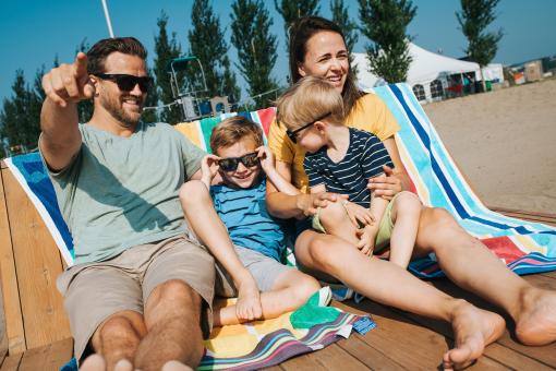 Une famille avec deux jeunes enfants relaxent sur des chaises longues à la plage de la Baie de Beauport.
