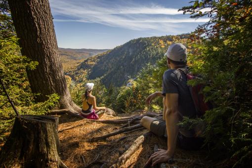 Hikers take a break in the forest and observe the landscapes in the Vallée Bras-du-Nord.