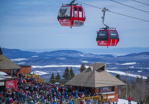 A crowd of people at the top of the mountain at the Mont-Sainte-Anne ski center.