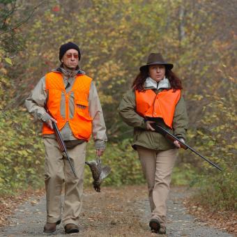 Two hunters, rifles in hand, on a trail in autumn, in the Portneuf Wildlife Reserve.