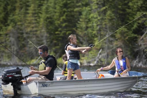 Family fishing in the Réserve faunique des Laurentides, aboard a rowboat, on a beautiful sunny summer day.