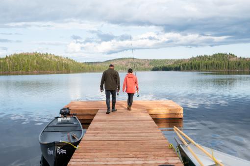 A couple is fishing in a lake at the end of the wharf in the Réserve faunique des Laurentides in fall.