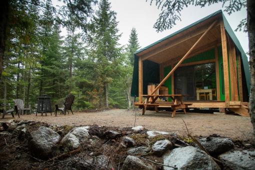 Exterior view of ready-to-camp accommodation in the forest in the Réserve faunique des Laurentides, in summer.