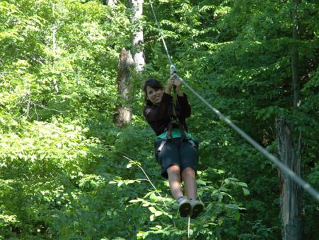 A woman on a zip line in the forest of the Station touristique Duchesnay.