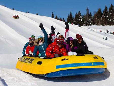 Un groupe de personne fait une descente en rafting des neiges au Village Vacances Valcartier, en hiver.