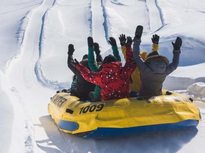 Un groupe fait du rafting sur neige, les bras dans les airs, dans une glissade du Village Vacances Valcartier.
