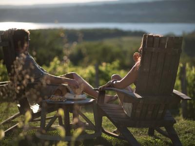 Un couple assis dans un vignoble prend une pause gourmande et contemple le paysage de l'le d'Orléans. 