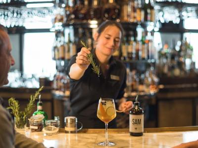 A barmaid serves alcohol to a couple seated at the bar of the restaurant Le Sam, at the Fairmont Le Château Frontenac hotel.
