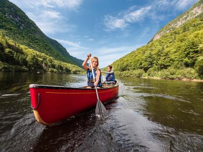 Two women canoe in the river at the bottom of the valley, in Jacques-Cartier National Park.