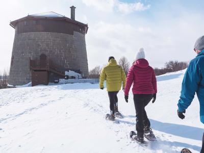 Three snowshoe hikers on the Plains of Abraham are heading towards Martello Tower no.1.