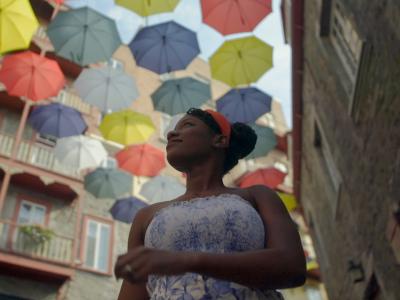 Oneika is walking under colorful umbrellas on Cul-de-Sac Street