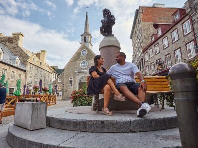 A couple is sitting on a bench on Place Royale