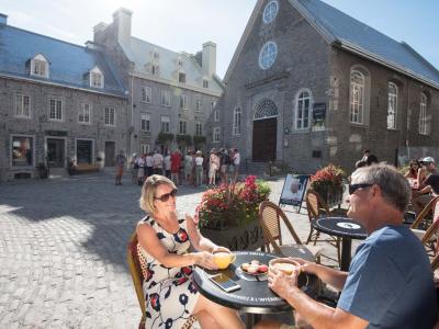 A couple drink a coffee next to Notre-Dame-des-Victoires Church, on the terrace of Maison Smith in Place Royale.