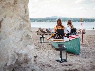 Two girls relax near a canoe on the beach at Baie de Beauport.