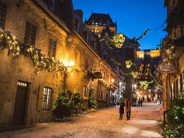A couple in love walks in the evening in the rue du Petit-Champlain illuminated for Christmas and the holidays.