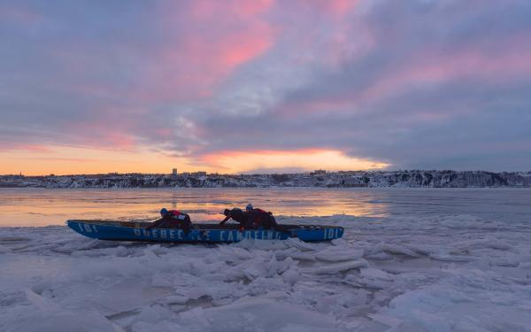 Quatre hommes en canot à glace sur le fleuve Saint-Laurent gelé, entre Québec et Lévis.