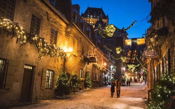 A couple in love walks in the evening in the rue du Petit-Champlain illuminated for Christmas and the holidays.